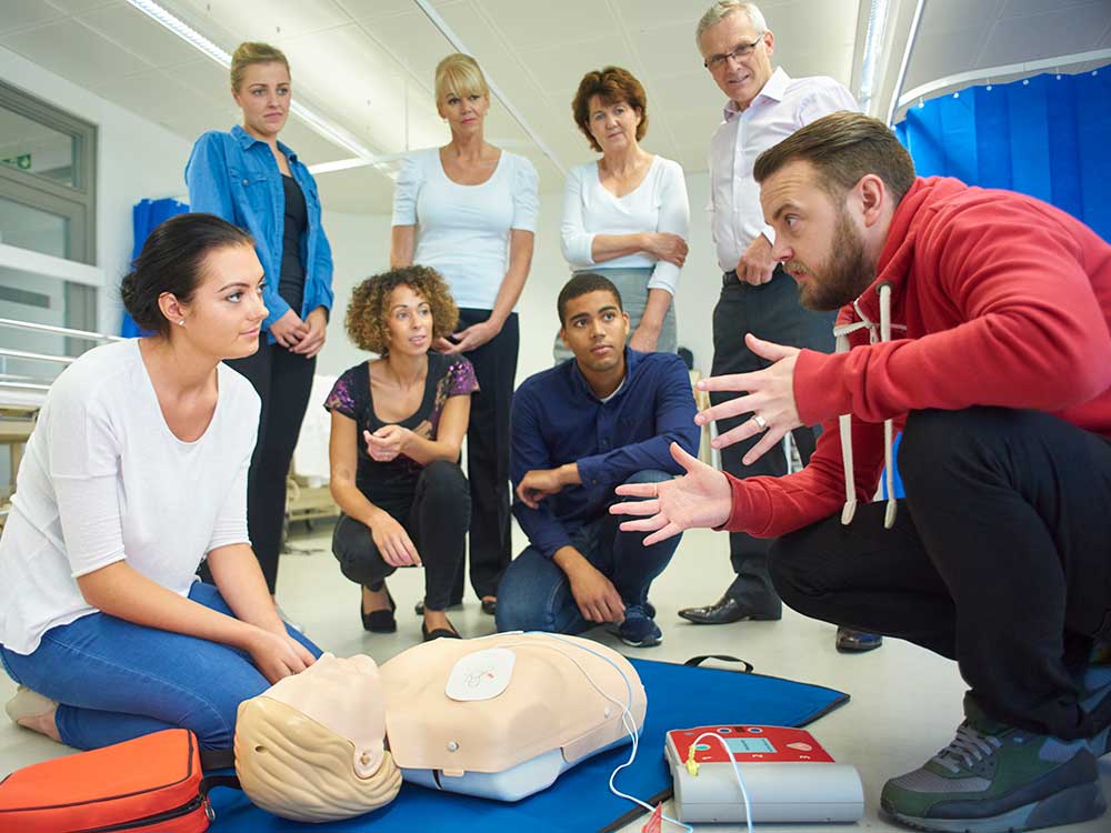 First aid instructor with students learning CPR